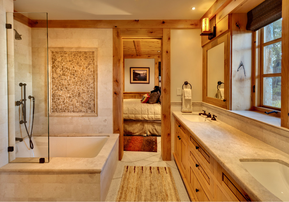На фото: ванная комната в стиле рустика с врезной раковиной, фасадами в стиле шейкер, фасадами цвета дерева среднего тона, полновстраиваемой ванной, душем над ванной, бежевой плиткой и бежевыми стенами с