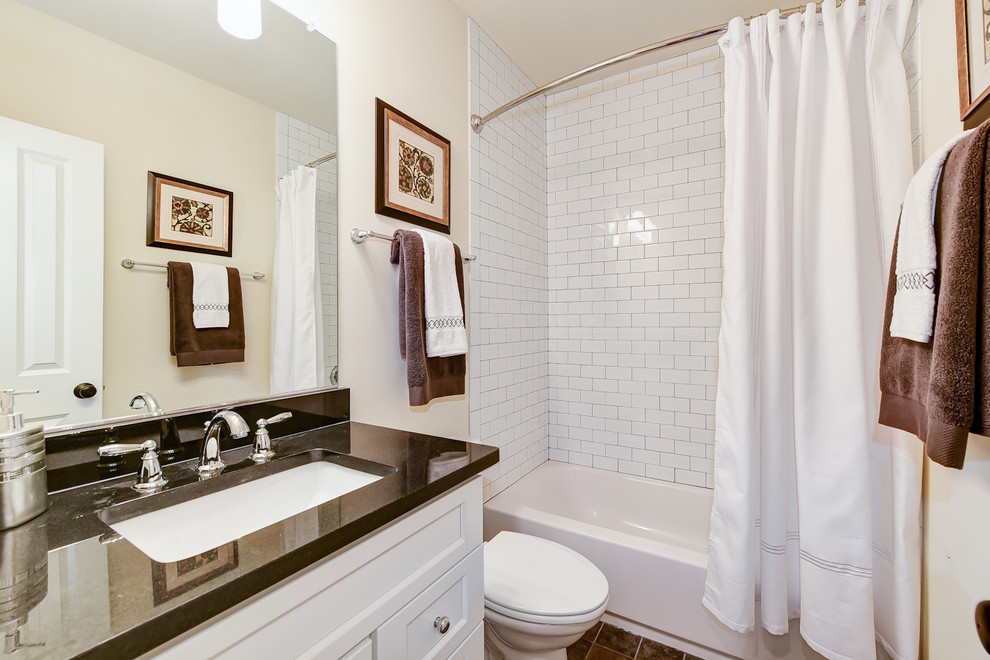 Bild på ett vintage badrum, med luckor med infälld panel, vita skåp, ett badkar i en alkov, en toalettstol med separat cisternkåpa, svart och vit kakel, keramikplattor, klinkergolv i keramik, ett undermonterad handfat och granitbänkskiva