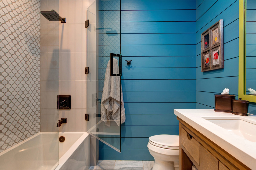 Cette image montre une salle d'eau traditionnelle en bois brun de taille moyenne avec un plan de toilette en quartz, un combiné douche/baignoire, des carreaux de céramique, un mur bleu, un lavabo encastré, un carrelage multicolore, un placard à porte plane, une baignoire en alcôve, WC séparés, un sol en carrelage de porcelaine, un sol gris, une cabine de douche à porte battante et un plan de toilette blanc.
