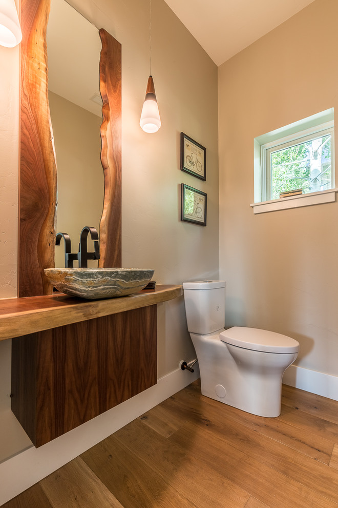 Cette photo montre un WC et toilettes nature en bois foncé avec un mur beige, un sol en bois brun et un plan de toilette en bois.