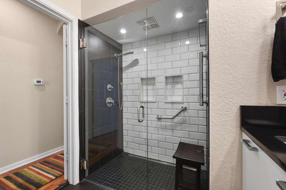 Стильный дизайн: маленькая главная ванная комната в стиле модернизм с плоскими фасадами, белыми фасадами, душем в нише, инсталляцией, черно-белой плиткой, керамогранитной плиткой, бежевыми стенами, полом из керамогранита, врезной раковиной, столешницей из искусственного кварца, черным полом, душем с распашными дверями и черной столешницей для на участке и в саду - последний тренд