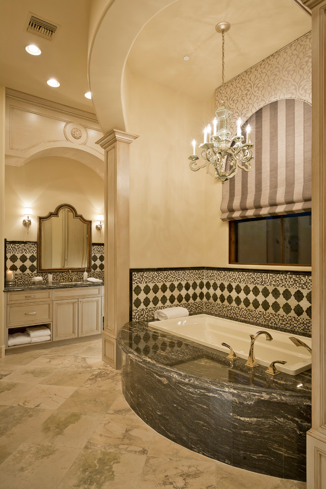 Diseño de cuarto de baño azulejo de dos tonos mediterráneo con armarios con paneles empotrados, puertas de armario beige, bañera encastrada y baldosas y/o azulejos multicolor