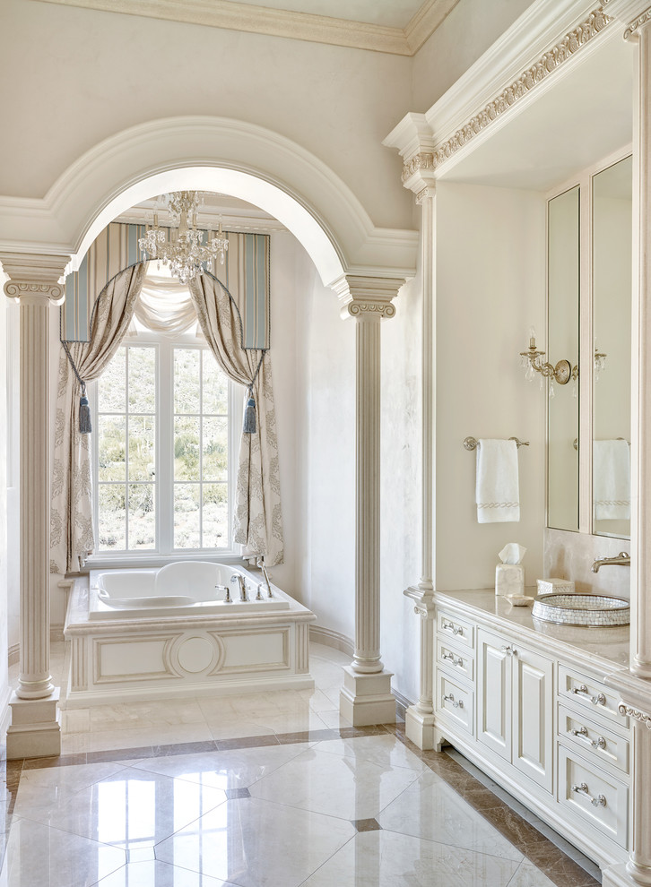 Exemple d'une salle de bain principale chic avec un placard avec porte à panneau surélevé, des portes de placard beiges, une baignoire posée, un mur beige et une fenêtre.