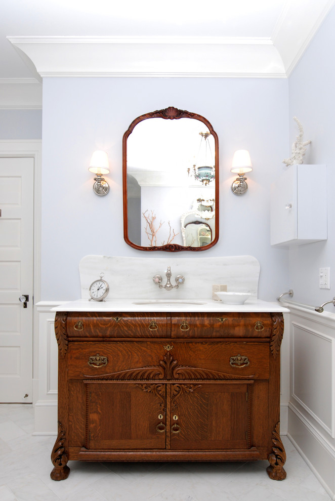 Modelo de cuarto de baño clásico con lavabo bajoencimera, puertas de armario de madera en tonos medios y armarios con paneles empotrados