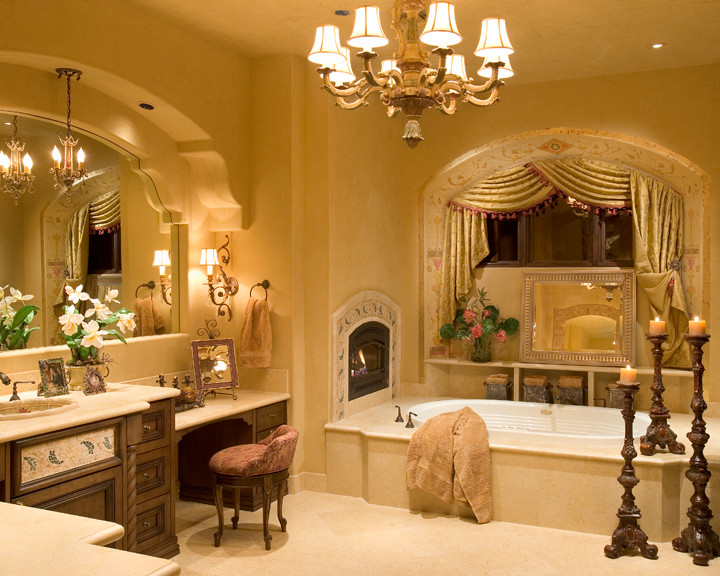 Großes Mediterranes Badezimmer En Suite mit dunklen Holzschränken, Einbaubadewanne, beigen Fliesen, gelber Wandfarbe, Einbauwaschbecken, Marmor-Waschbecken/Waschtisch und beigem Boden in Phoenix