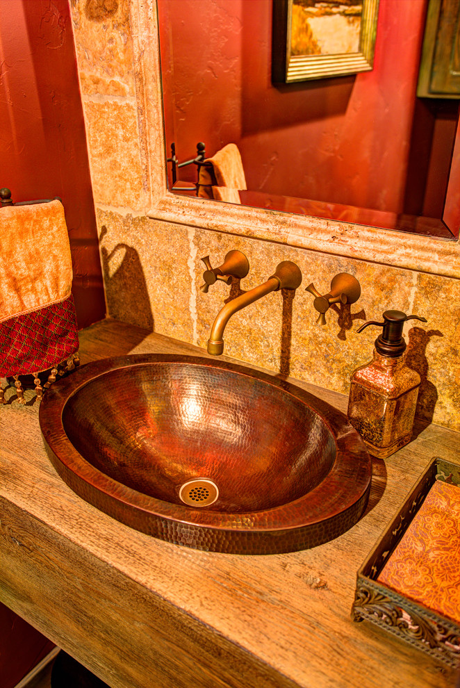 Foto de cuarto de baño rústico pequeño con lavabo sobreencimera, encimera de madera, baldosas y/o azulejos beige, baldosas y/o azulejos de piedra, paredes rojas y suelo de madera en tonos medios