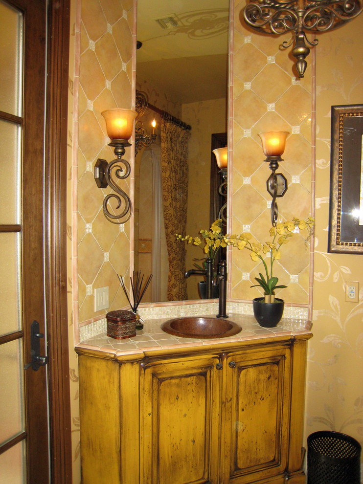 Источник вдохновения для домашнего уюта: ванная комната в средиземноморском стиле с накладной раковиной, искусственно-состаренными фасадами, столешницей из плитки и бежевой плиткой