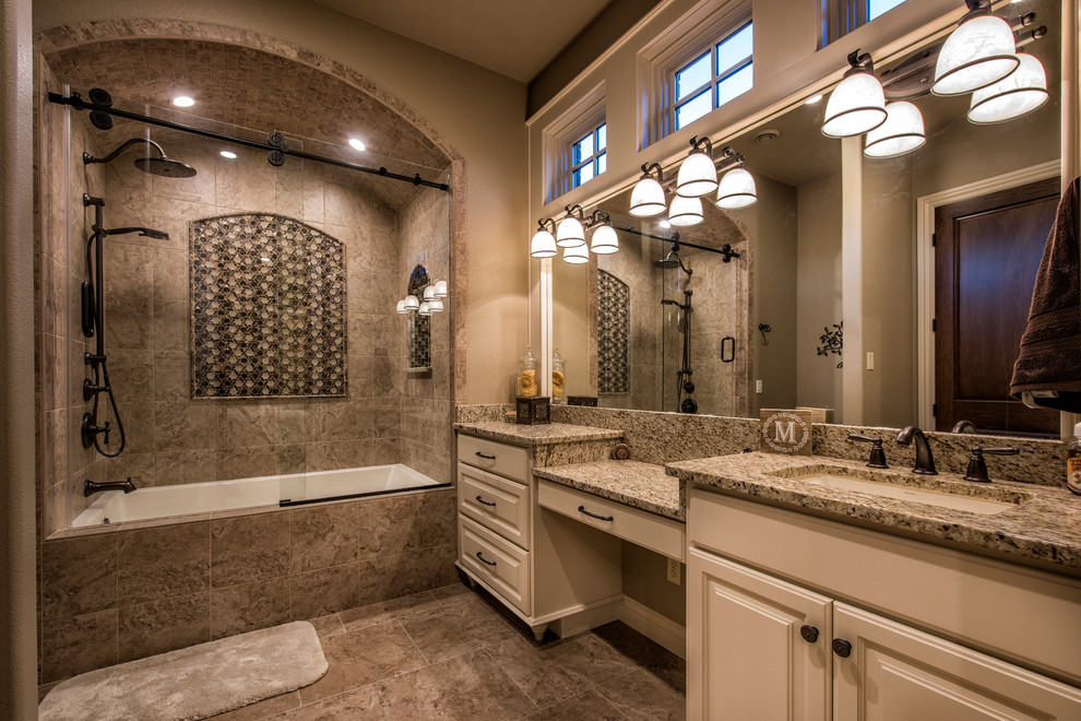 Inredning av ett klassiskt stort badrum med dusch, med luckor med upphöjd panel, ett badkar i en alkov, ett undermonterad handfat, granitbänkskiva, vita skåp, en dusch/badkar-kombination, grå kakel, porslinskakel, beige väggar och klinkergolv i porslin