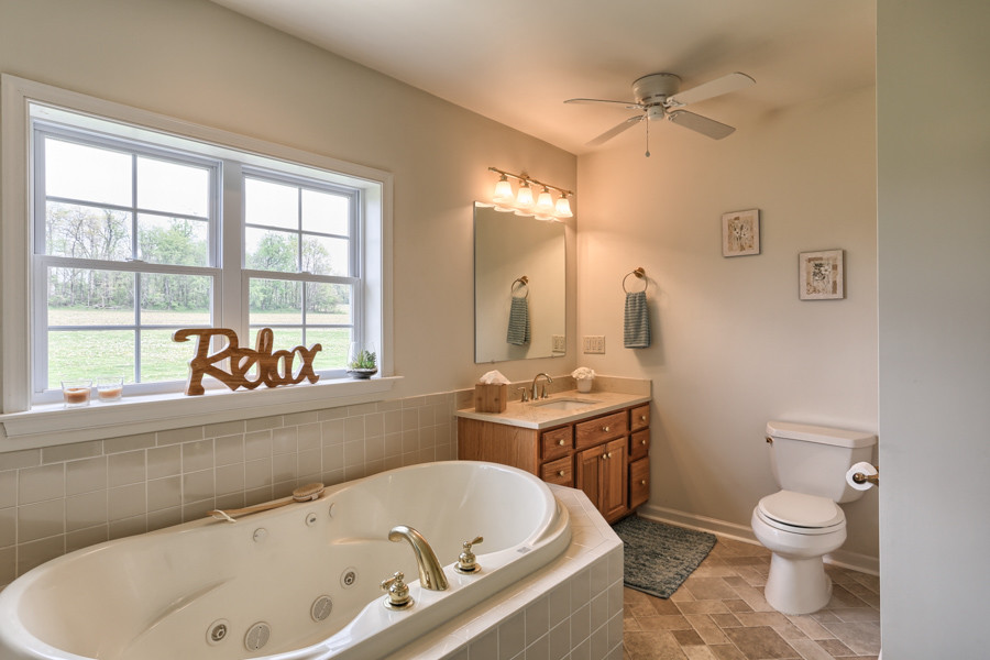 Esempio di una stanza da bagno padronale tradizionale con ante con bugna sagomata, ante in legno scuro, vasca idromassaggio, pareti beige, lavabo sottopiano e pavimento beige
