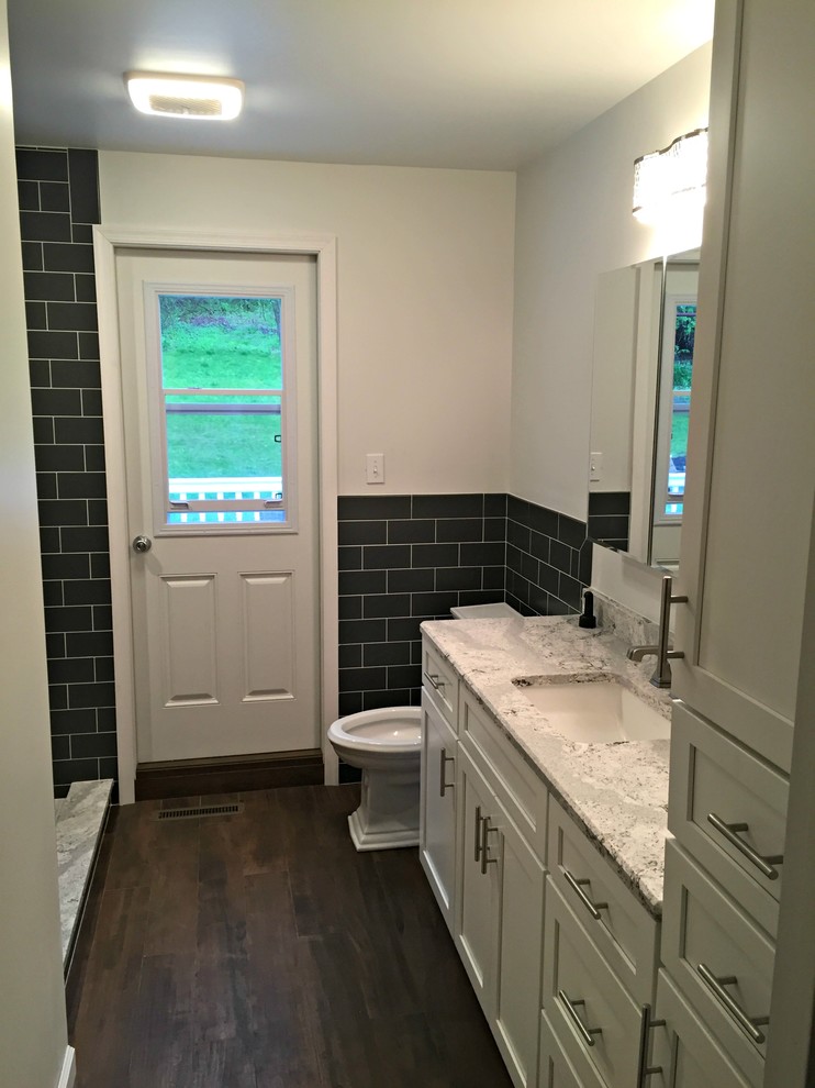 Mid-sized trendy 3/4 black tile and subway tile dark wood floor doorless shower photo in Philadelphia with shaker cabinets, white cabinets, a two-piece toilet, white walls, an undermount sink and granite countertops