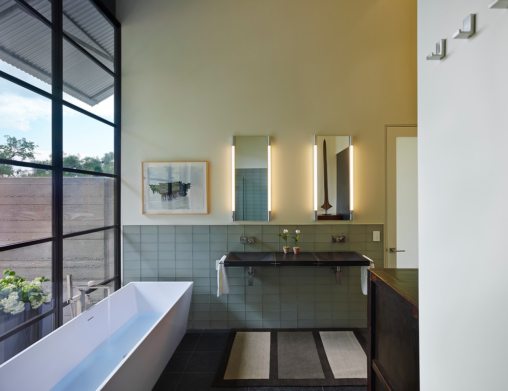 Стильный дизайн: ванная комната в современном стиле с подвесной раковиной, отдельно стоящей ванной, серой плиткой, стеклянной плиткой и бежевыми стенами - последний тренд