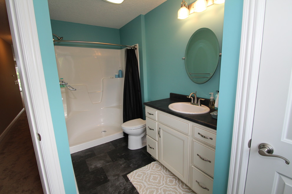 Inredning av ett maritimt mellanstort badrum, med ett nedsänkt handfat, skåp i mellenmörkt trä, laminatbänkskiva, en kantlös dusch, svart kakel, blå väggar och klinkergolv i keramik