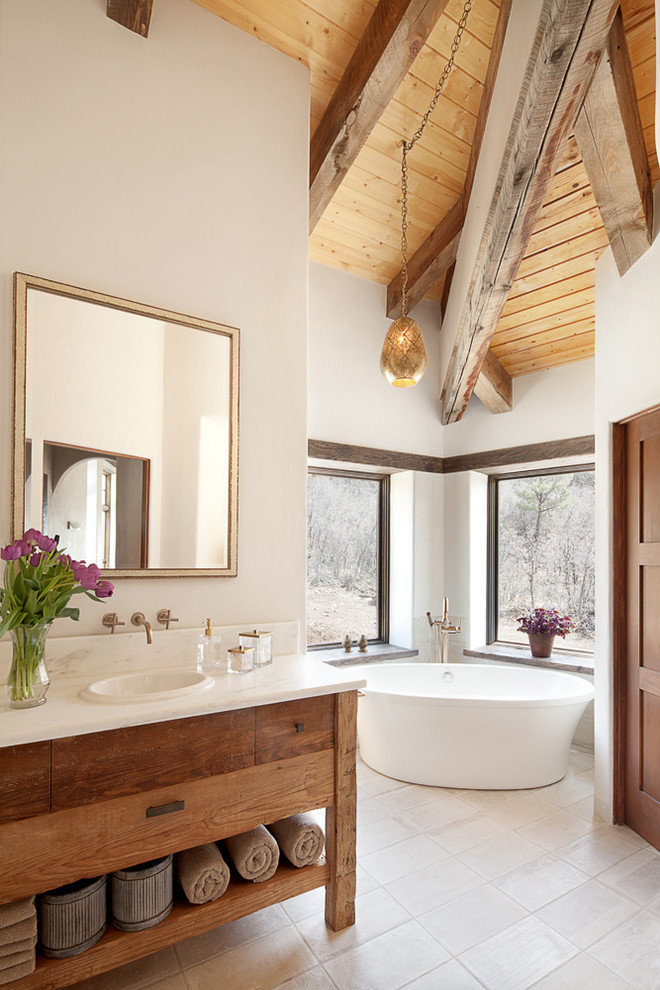 На фото: главная ванная комната в стиле фьюжн с коричневыми фасадами, отдельно стоящей ванной, белыми стенами, бежевым полом и плоскими фасадами