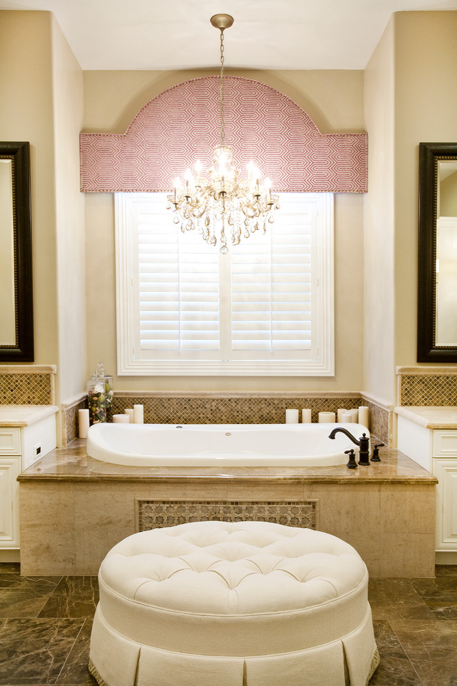 Réalisation d'une salle de bain principale tradition de taille moyenne avec des portes de placard blanches, une baignoire posée, un carrelage beige, un placard avec porte à panneau surélevé, un carrelage de pierre, un mur beige, un sol en marbre et un plan de toilette en marbre.