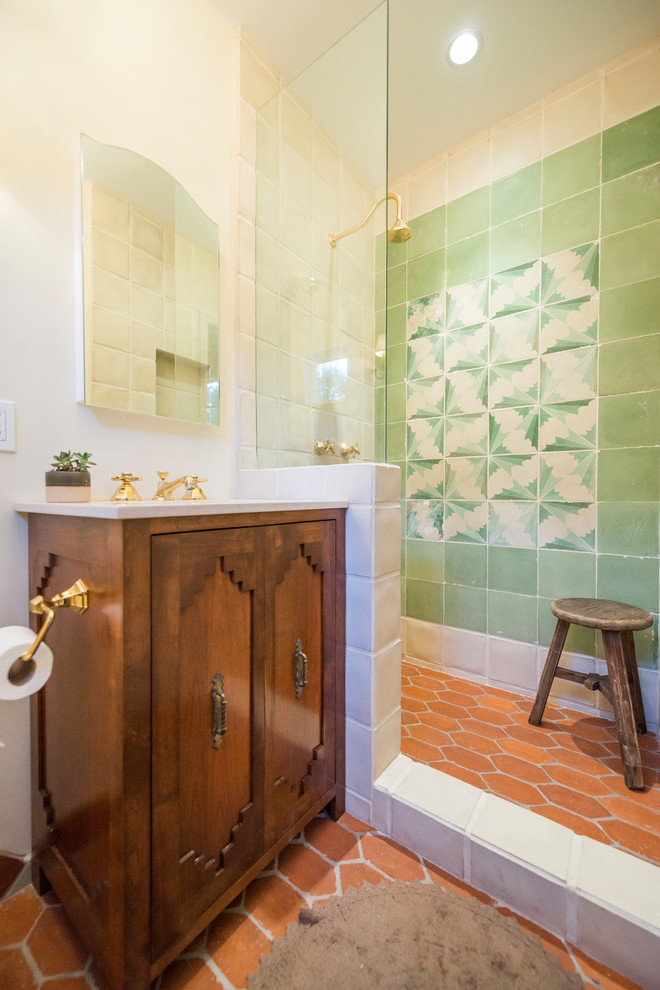 Foto på ett amerikanskt vit badrum med dusch, med skåp i mellenmörkt trä, en dusch i en alkov, grön kakel, vita väggar, klinkergolv i terrakotta, rött golv, med dusch som är öppen och luckor med infälld panel