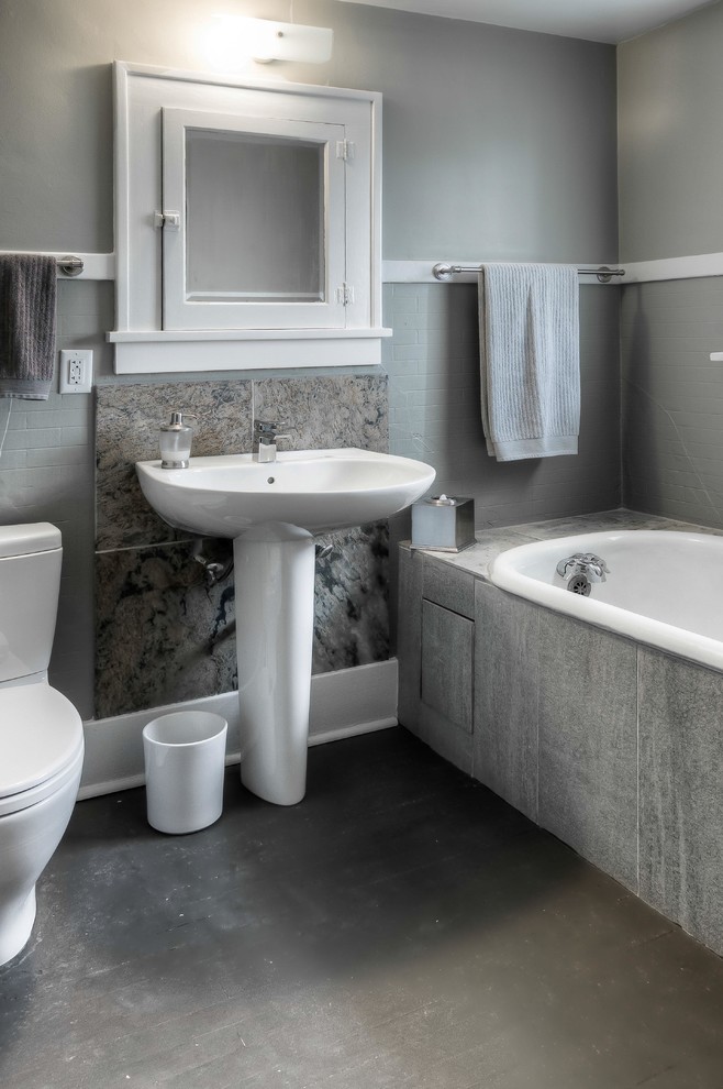 Kleines Modernes Duschbad mit Sockelwaschbecken, Einbaubadewanne, grauen Fliesen, offenen Schränken, Toilette mit Aufsatzspülkasten, Porzellanfliesen, grauer Wandfarbe, Betonboden und grauem Boden in Omaha