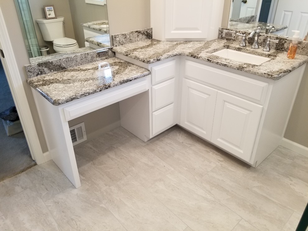 This is an example of a medium sized classic ensuite bathroom in Omaha with raised-panel cabinets, white cabinets, a corner shower, grey tiles, beige walls, a submerged sink, beige floors and a hinged door.