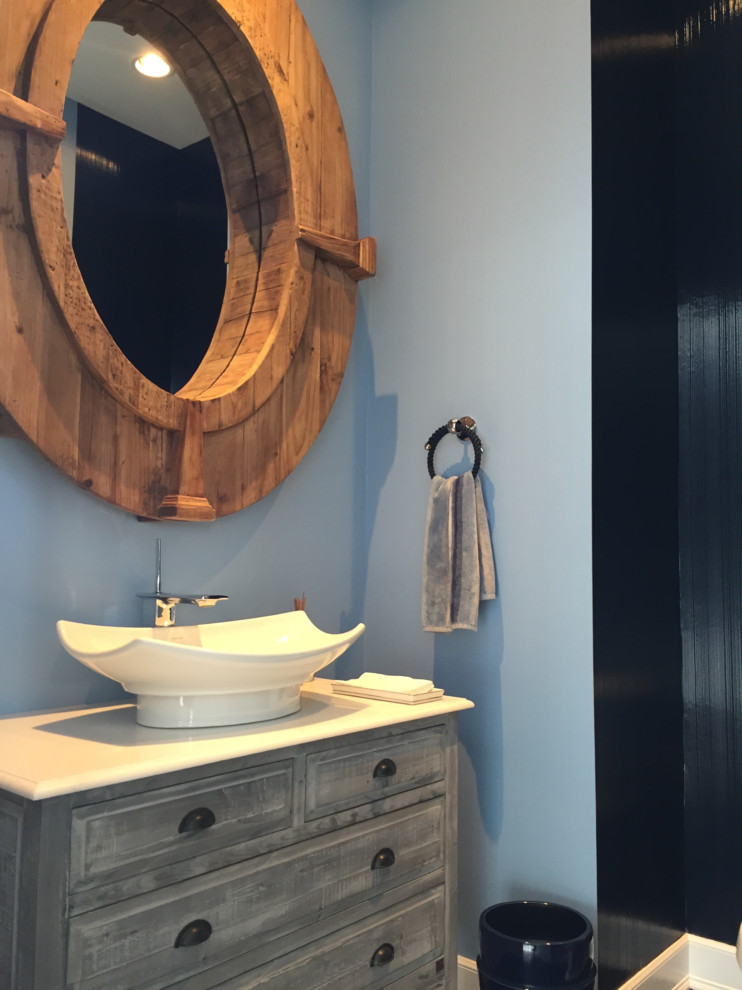 Maritim inredning av ett litet badrum med dusch, med möbel-liknande, skåp i slitet trä, en toalettstol med separat cisternkåpa, grå kakel, keramikplattor, blå väggar, klinkergolv i keramik, ett fristående handfat och bänkskiva i kvartsit