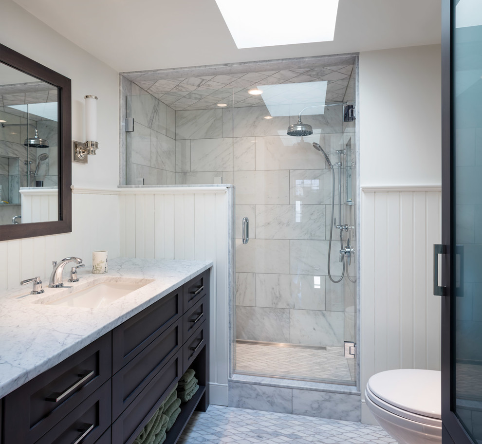 Photo of a small beach style shower room bathroom in Providence with flat-panel cabinets, dark wood cabinets, an alcove shower, a one-piece toilet, multi-coloured tiles, marble tiles, white walls, mosaic tile flooring, a submerged sink, marble worktops, white floors and a hinged door.
