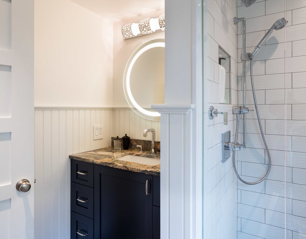 Inredning av ett maritimt litet badrum med dusch, med släta luckor, skåp i mörkt trä, en dusch i en alkov, en toalettstol med hel cisternkåpa, vit kakel, marmorkakel, vita väggar, mosaikgolv, ett undermonterad handfat, granitbänkskiva, vitt golv och dusch med gångjärnsdörr
