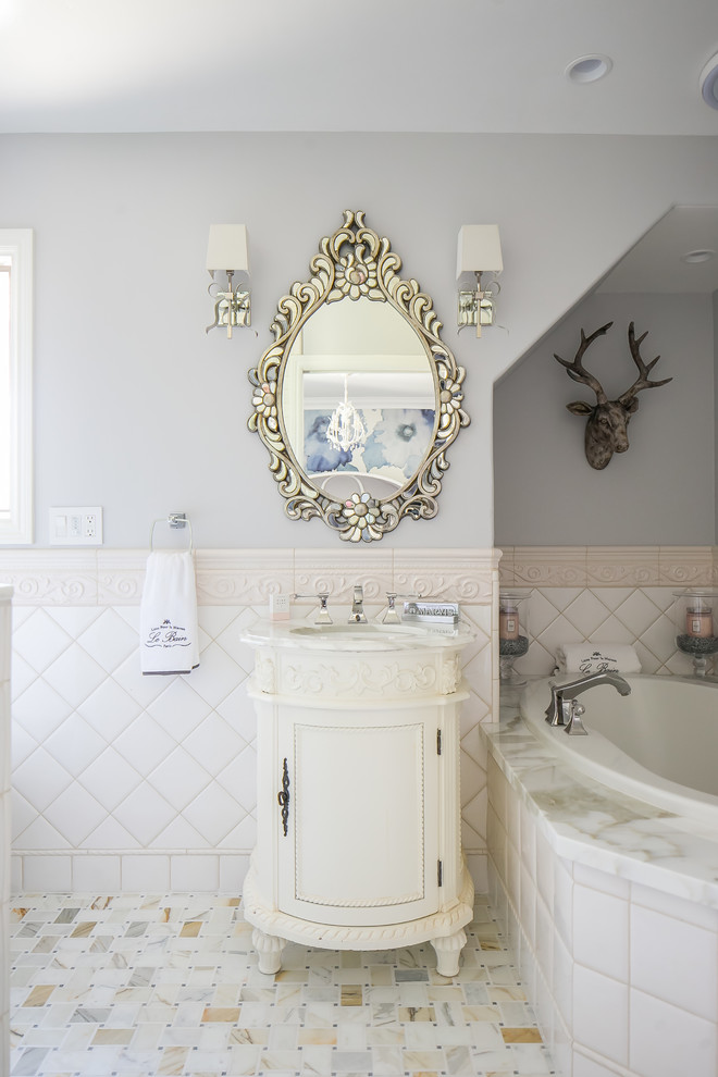 Example of a mid-sized ornate master white tile and porcelain tile porcelain tile and multicolored floor alcove bathtub design in Orange County with raised-panel cabinets, white cabinets, gray walls and marble countertops