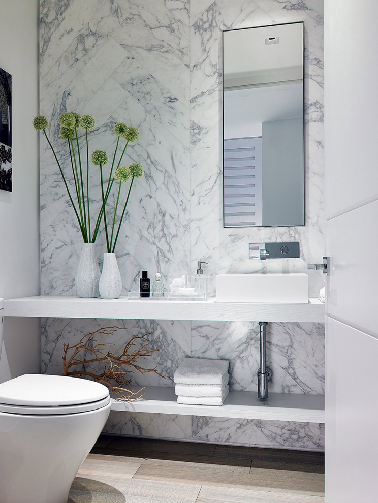 Design ideas for a contemporary bathroom in Miami with open cabinets, white cabinets, grey tiles, white tiles, stone slabs, white walls, medium hardwood flooring, a vessel sink and solid surface worktops.