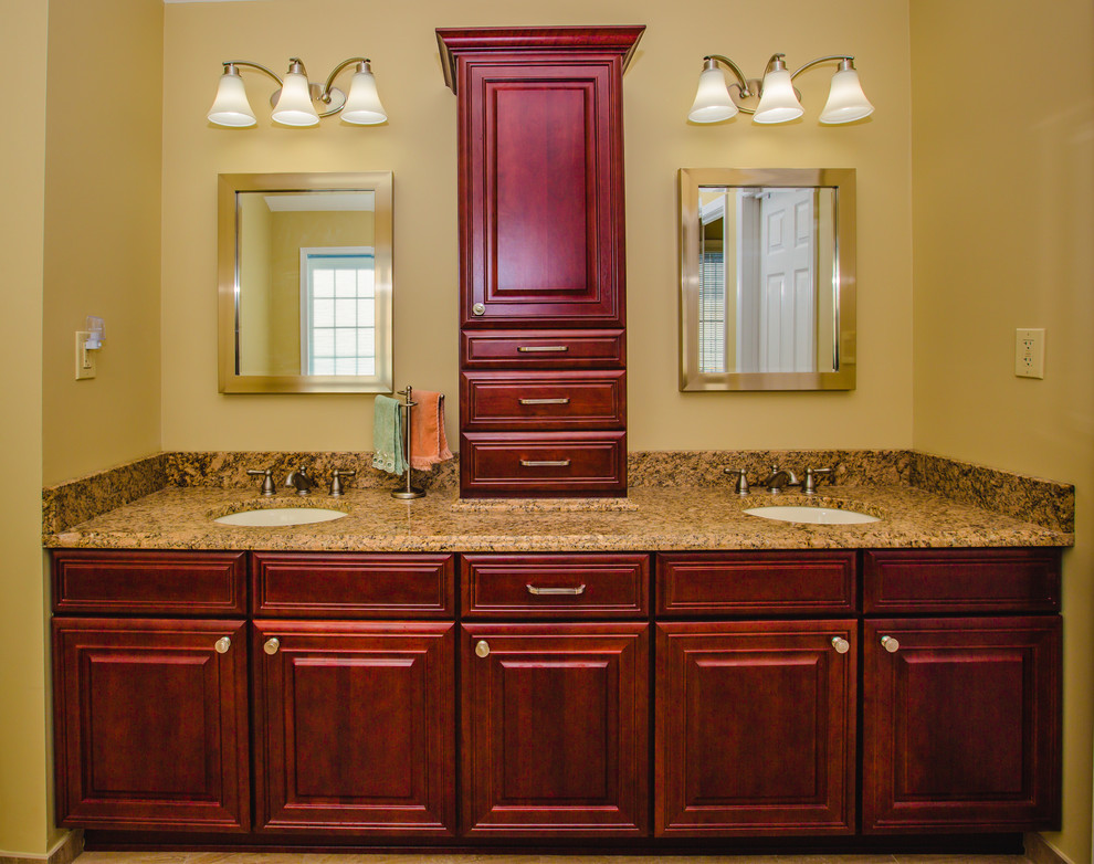 Cette image montre une grande salle de bain principale design avec un placard avec porte à panneau surélevé, des portes de placard rouges, une douche d'angle, un mur jaune, un sol en travertin, un lavabo encastré et un plan de toilette en granite.