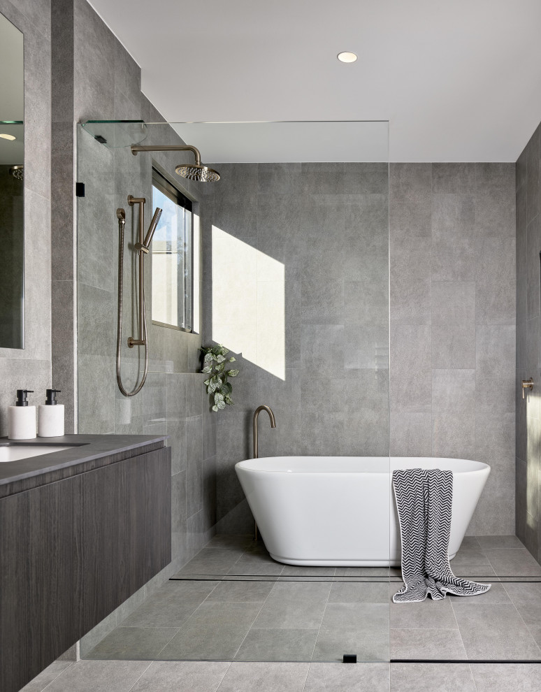 Inspiration pour une salle de bain principale minimaliste avec un placard à porte plane, des portes de placard grises, une baignoire indépendante, un carrelage gris, un lavabo encastré, un sol gris et un plan de toilette gris.