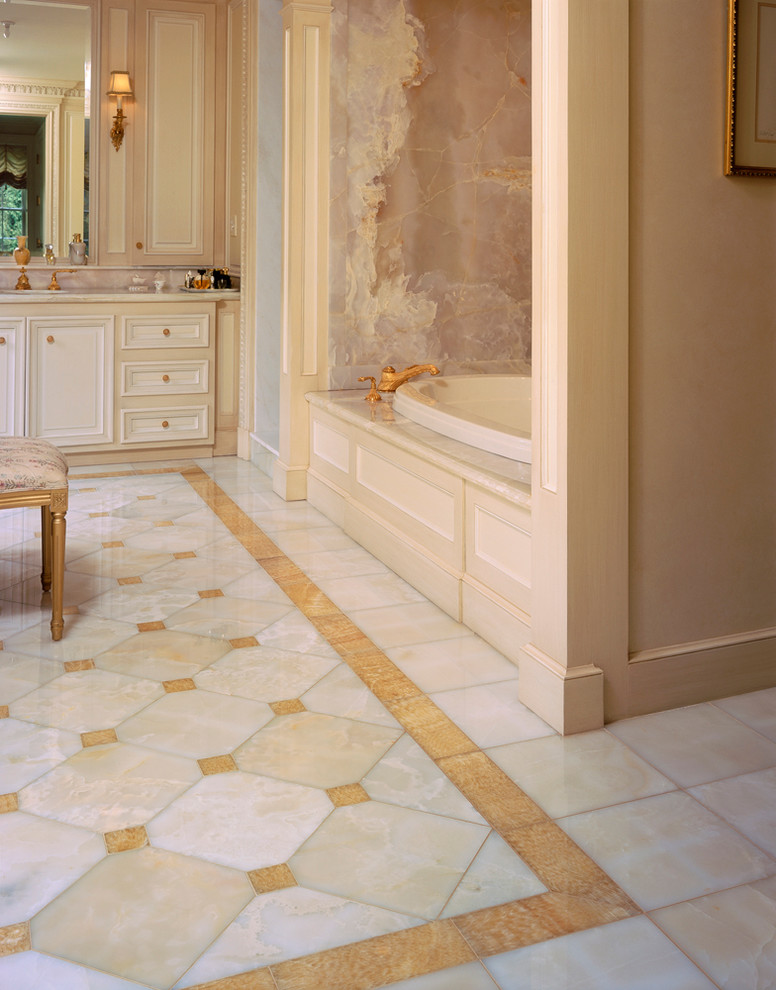 Exemple d'une grande salle de bain principale avec un lavabo encastré, un placard avec porte à panneau encastré, des portes de placard beiges, un plan de toilette en onyx, une baignoire posée, un carrelage multicolore, un carrelage de pierre, un mur beige et un sol en marbre.