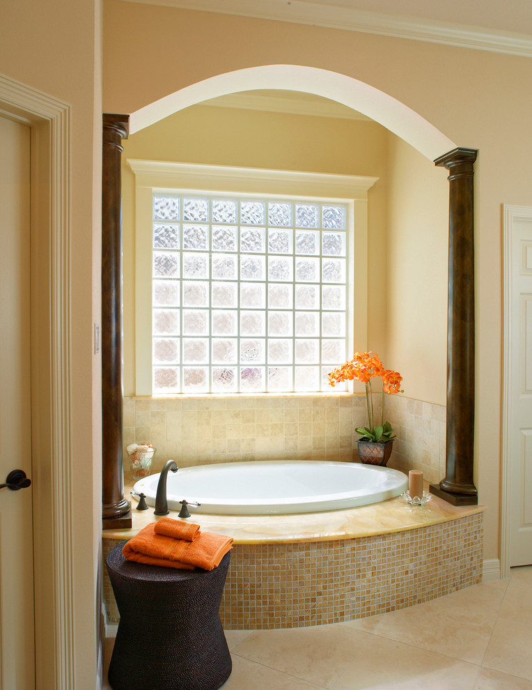 Diseño de cuarto de baño principal mediterráneo de tamaño medio con bañera encastrada, ducha esquinera, paredes beige, suelo de travertino y lavabo bajoencimera