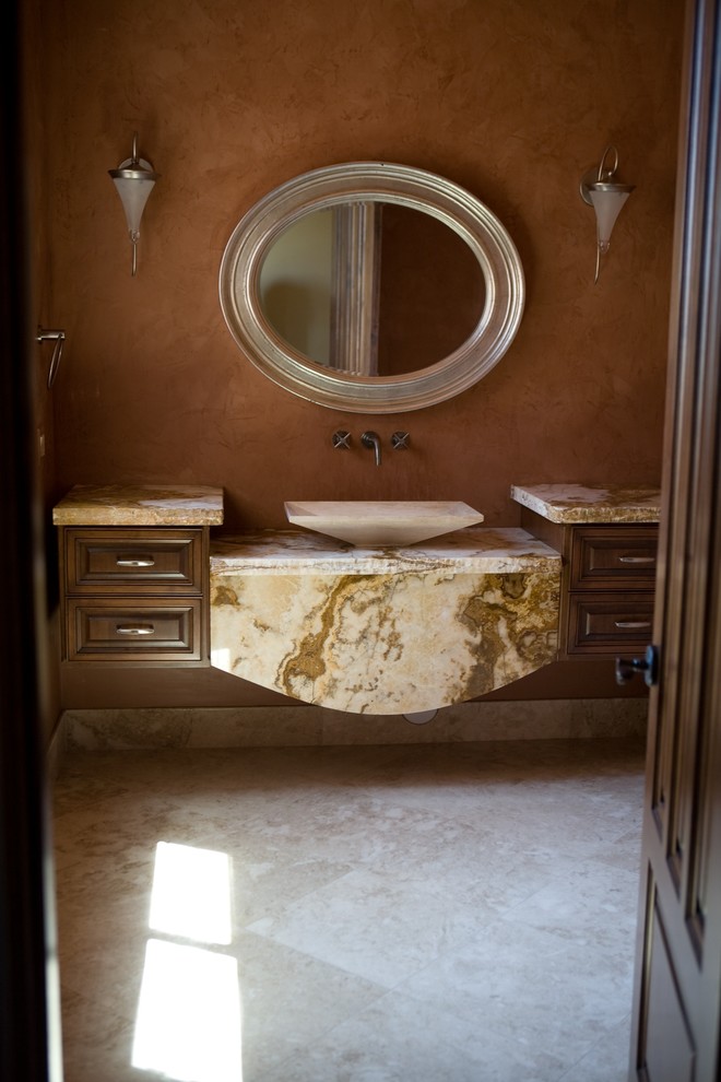 Réalisation d'une salle de bain tradition en bois brun avec un placard avec porte à panneau surélevé, un carrelage beige, un mur orange, un sol en travertin et un plan de toilette en onyx.
