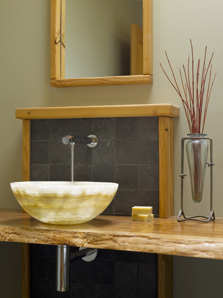 Imagen de cuarto de baño rural pequeño con lavabo sobreencimera, encimera de madera, baldosas y/o azulejos grises, baldosas y/o azulejos de piedra, paredes verdes y encimeras marrones