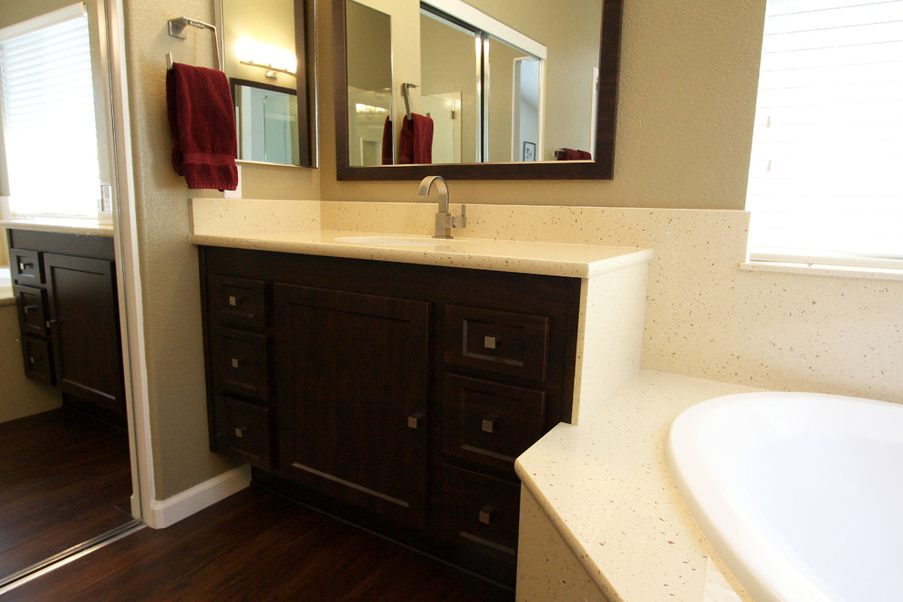 Cette photo montre une salle de bain chic en bois foncé avec une vasque, un placard à porte shaker, un plan de toilette en marbre, une baignoire d'angle, une douche d'angle, un mur beige et un sol en linoléum.