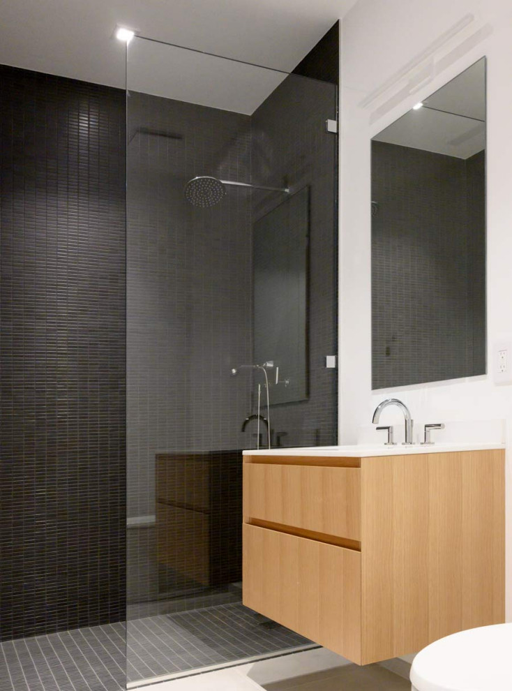 Inspiration for a large modern kids' black tile and ceramic tile ceramic tile and white floor bathroom remodel in New York with flat-panel cabinets, medium tone wood cabinets, white walls, a drop-in sink, solid surface countertops and white countertops