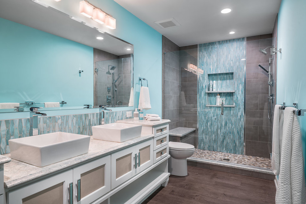 Photo of a large classic ensuite bathroom in Columbus with recessed-panel cabinets, a freestanding bath, an alcove shower, a one-piece toilet, blue tiles, ceramic tiles, grey walls, vinyl flooring, a vessel sink, engineered stone worktops, grey floors, a hinged door and white cabinets.