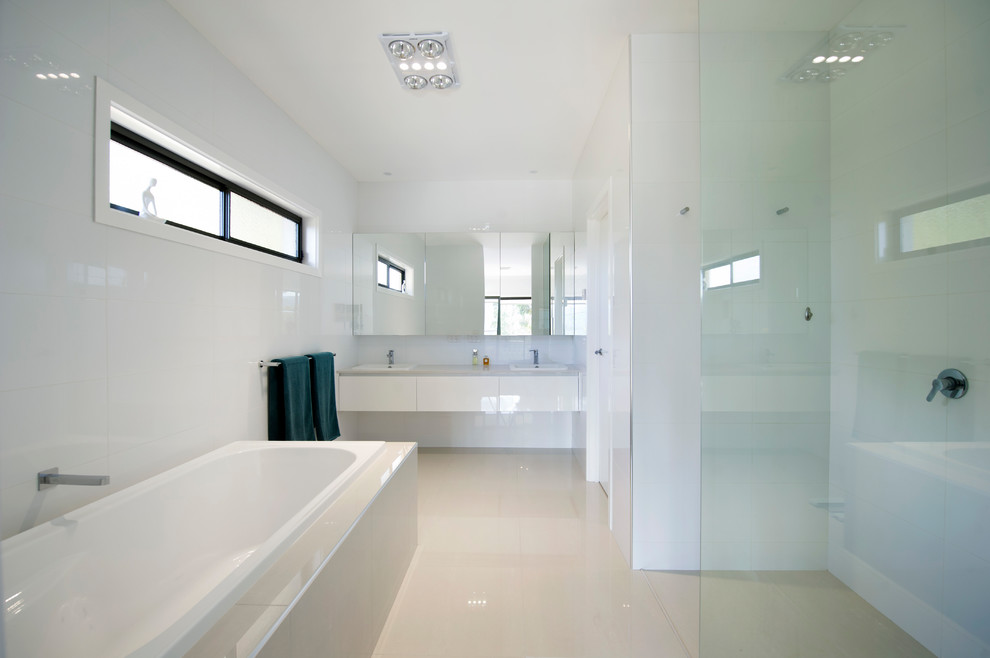 Пример оригинального дизайна: ванная комната в стиле модернизм с плоскими фасадами, белыми фасадами, накладной ванной, открытым душем, унитазом-моноблоком, белой плиткой, керамической плиткой, белыми стенами, полом из керамической плитки, подвесной раковиной, столешницей из искусственного кварца, белым полом и открытым душем
