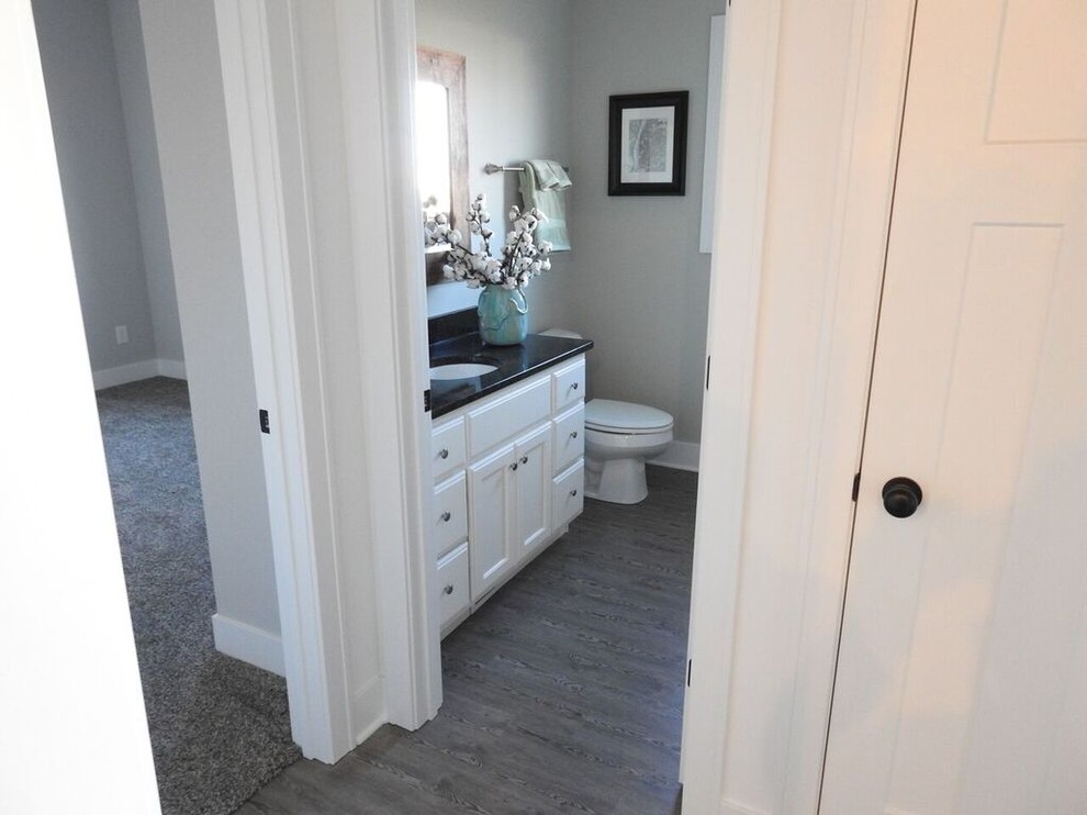 Klassisk inredning av ett stort badrum med dusch, med luckor med upphöjd panel, vita skåp, grå väggar, målat trägolv, ett undermonterad handfat och granitbänkskiva