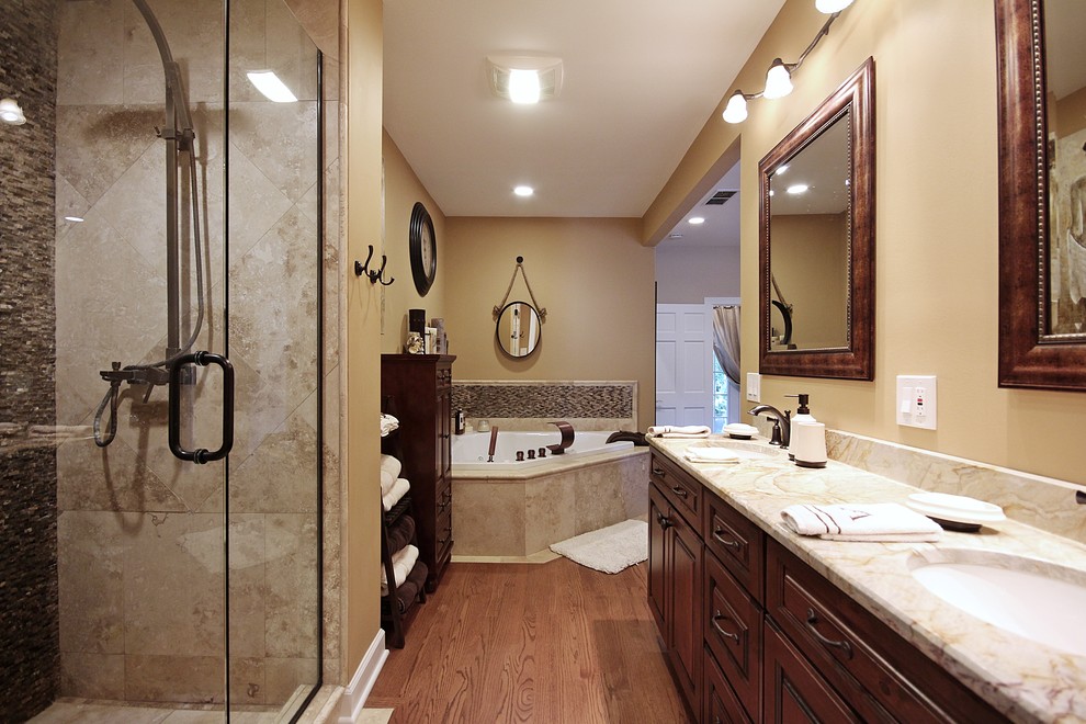 Bathroom - mid-sized rustic master beige tile and porcelain tile medium tone wood floor bathroom idea in Chicago with an undermount sink, raised-panel cabinets, dark wood cabinets, limestone countertops, a one-piece toilet and beige walls