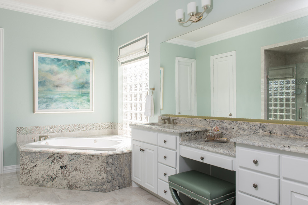 Inredning av ett klassiskt stort en-suite badrum, med ett undermonterad handfat, luckor med upphöjd panel, vita skåp, granitbänkskiva, ett hörnbadkar, en dusch i en alkov, grå kakel, porslinskakel, grå väggar och klinkergolv i porslin