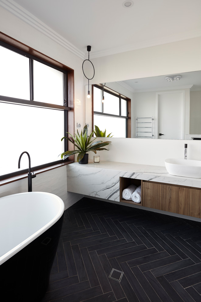 Modern inredning av ett stort en-suite badrum, med ett fristående badkar, vita väggar, ett fristående handfat, svart golv, en dusch i en alkov, en vägghängd toalettstol, keramikplattor, klinkergolv i keramik och med dusch som är öppen