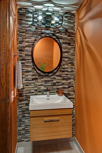 Idee per una piccola stanza da bagno minimalista con lavabo sospeso, ante lisce, ante in legno scuro, WC a due pezzi, piastrelle multicolore, piastrelle a mosaico, pareti arancioni e pavimento in gres porcellanato
