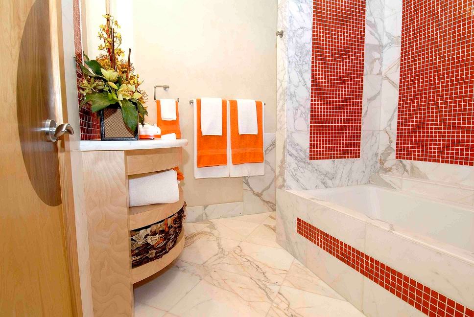 Bild på ett tropiskt badrum, med möbel-liknande, skåp i ljust trä, ett undermonterat badkar, en dusch/badkar-kombination, en toalettstol med hel cisternkåpa, glaskakel, beige väggar, marmorgolv, ett undermonterad handfat, marmorbänkskiva och röd kakel