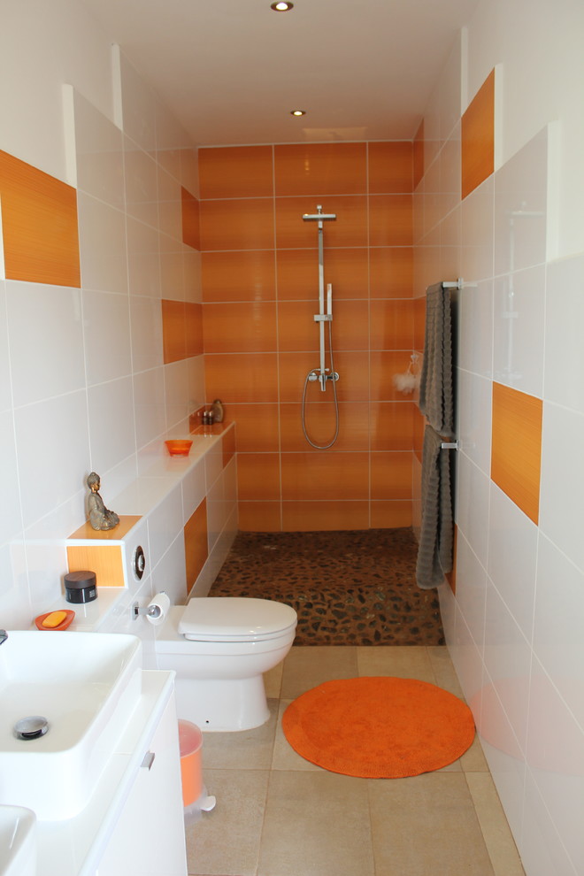 Cette photo montre une salle de bain tendance avec un plan vasque, un placard à porte plane, des portes de placard blanches, un plan de toilette en carrelage, une douche ouverte, WC à poser, un carrelage orange, des carreaux de céramique, un mur blanc et un sol en galet.