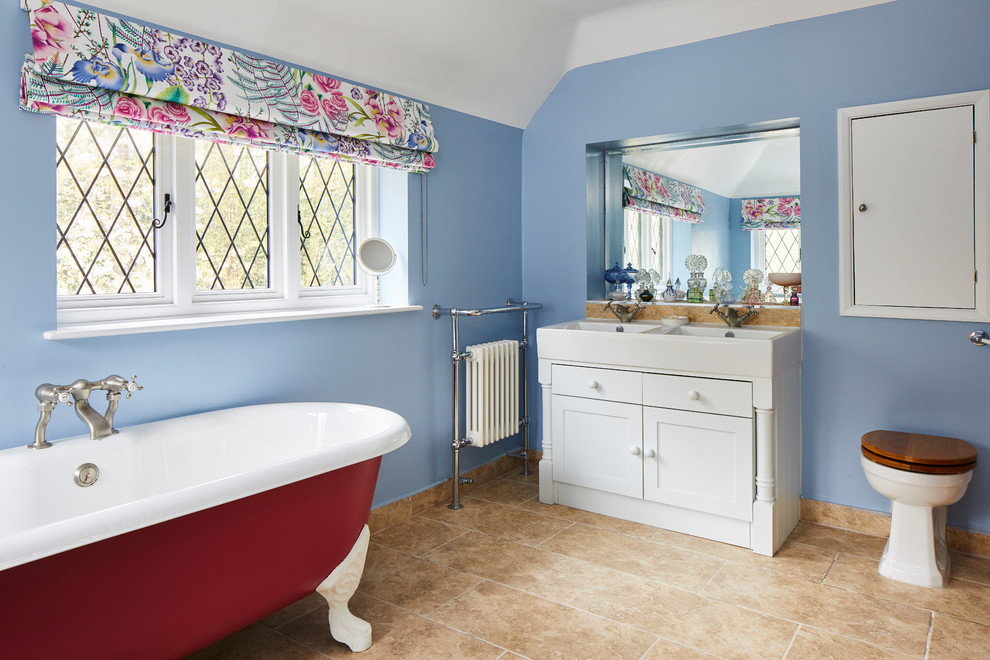 Inspiration for a classic bathroom in London with shaker cabinets, white cabinets, a claw-foot bath, a one-piece toilet, blue walls, a console sink and beige floors.