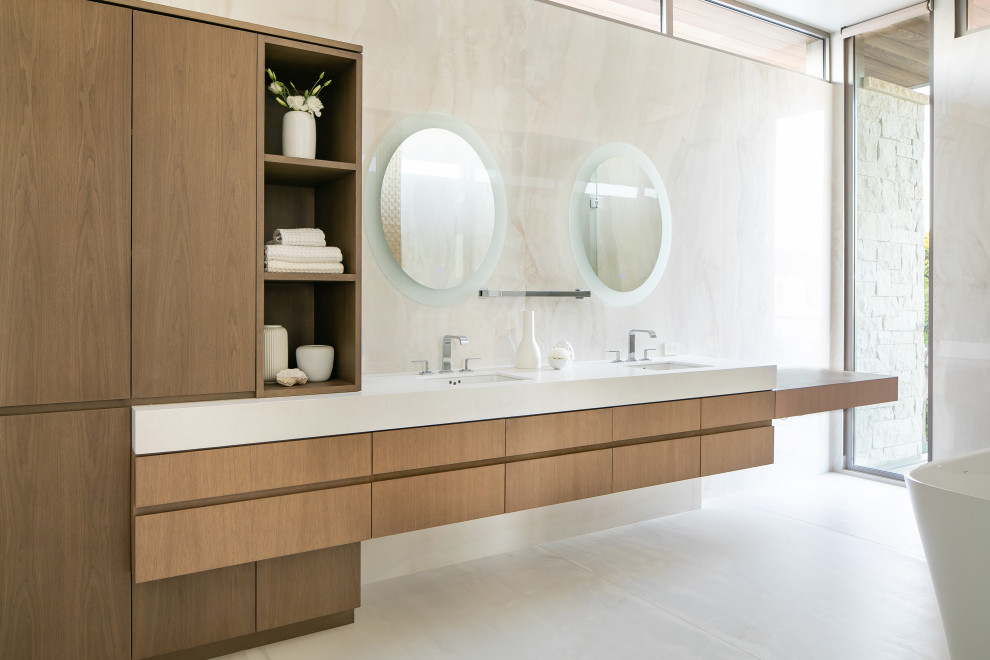 Exemple d'une salle de bain principale tendance en bois brun avec un placard à porte plane, une baignoire indépendante, un carrelage beige, un lavabo encastré, un sol beige, un plan de toilette blanc, meuble double vasque et meuble-lavabo suspendu.