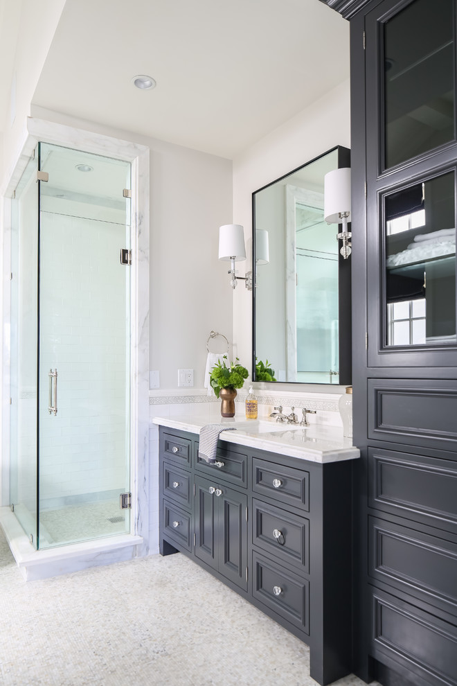 Modelo de cuarto de baño tradicional renovado con armarios con paneles empotrados, puertas de armario negras, ducha empotrada, paredes blancas, lavabo bajoencimera, suelo gris y encimeras blancas