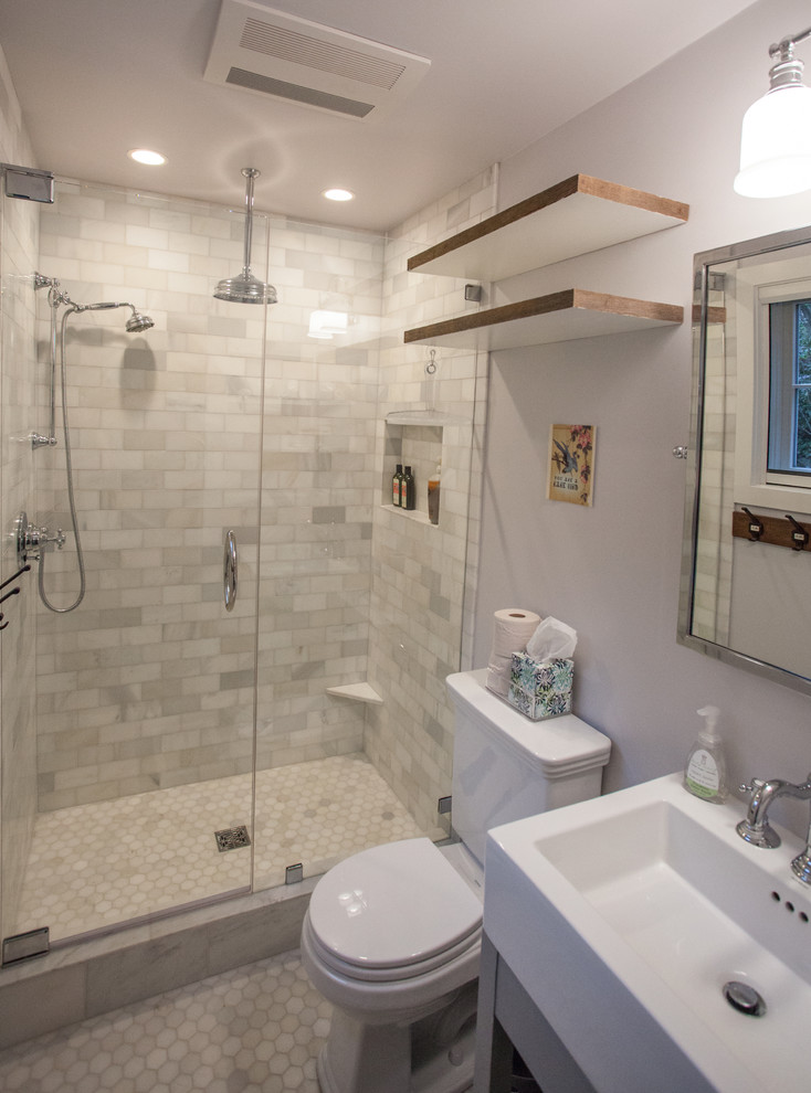 Foto på ett litet lantligt badrum med dusch, med öppna hyllor, grå skåp, en dusch i en alkov, en toalettstol med separat cisternkåpa, vit kakel, stenkakel, vita väggar, marmorgolv och ett konsol handfat