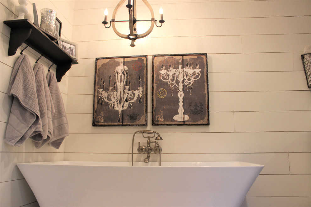Пример оригинального дизайна: главная ванная комната среднего размера в стиле кантри с фасадами в стиле шейкер, серыми фасадами, отдельно стоящей ванной, угловым душем, белыми стенами, полом из керамогранита, монолитной раковиной, мраморной столешницей, черным полом, душем с распашными дверями, серой столешницей, тумбой под одну раковину, напольной тумбой и стенами из вагонки