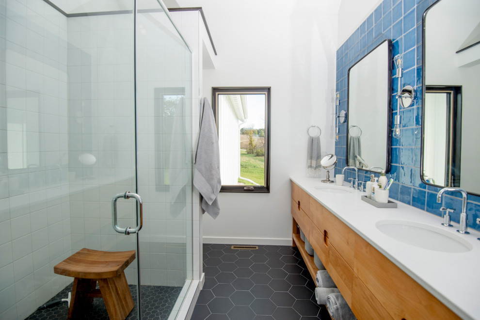 Medium sized classic ensuite bathroom in Other with flat-panel cabinets, medium wood cabinets, an alcove shower, blue tiles, glass tiles, white walls, a submerged sink, black floors, a hinged door and white worktops.