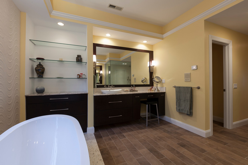 Свежая идея для дизайна: большая главная ванная комната в современном стиле с настольной раковиной, плоскими фасадами, темными деревянными фасадами, столешницей из оникса, отдельно стоящей ванной, угловым душем, раздельным унитазом, бежевой плиткой, керамогранитной плиткой, желтыми стенами и полом из керамогранита - отличное фото интерьера